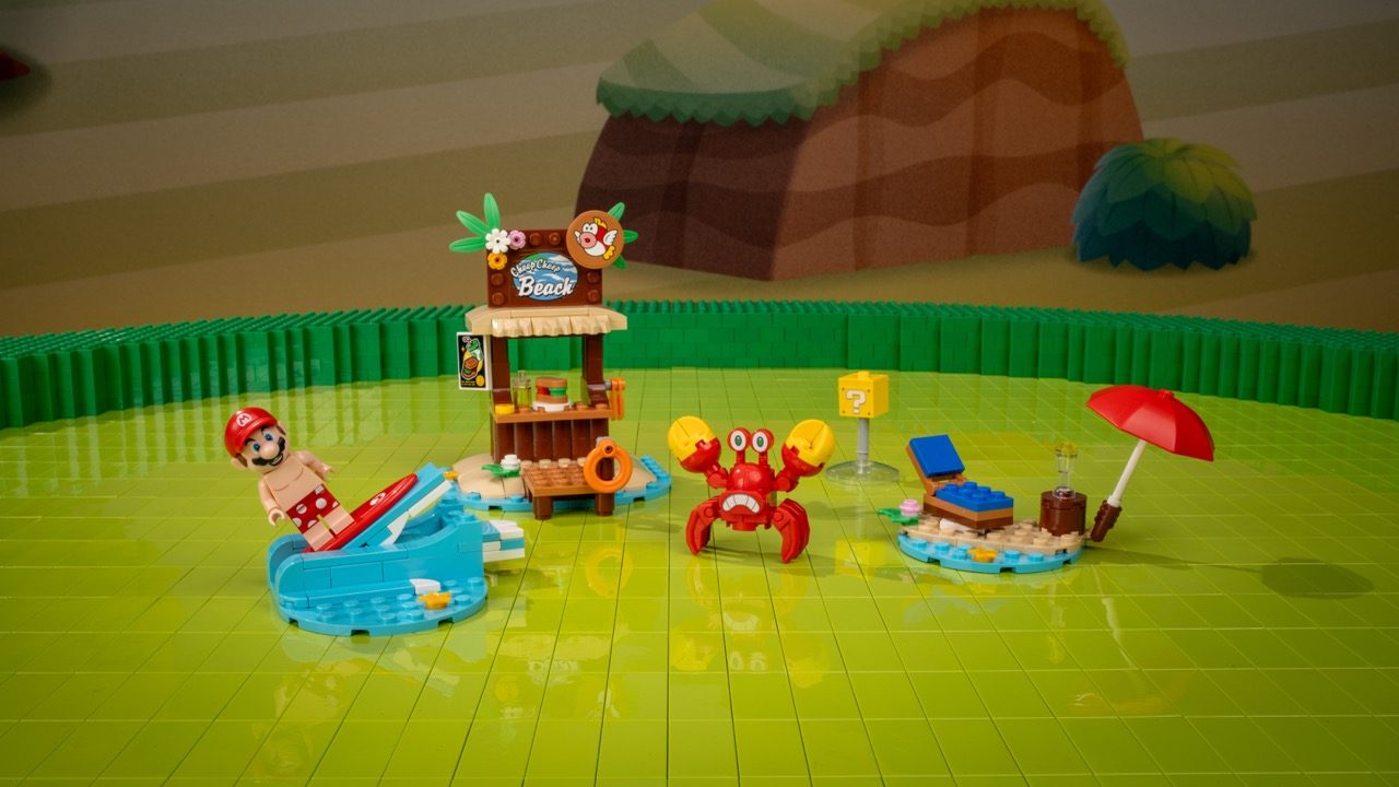 LEGO Super Mario beach set with Mario minifigure, crab enemy, beach hut, pool, and umbrella on green baseplate.