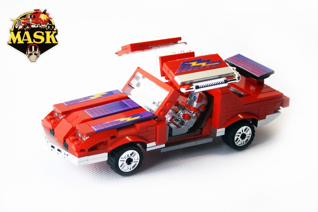 LEGO M.A.S.K. red vehicle with opening cockpit, solar panels, and white wheels on display.