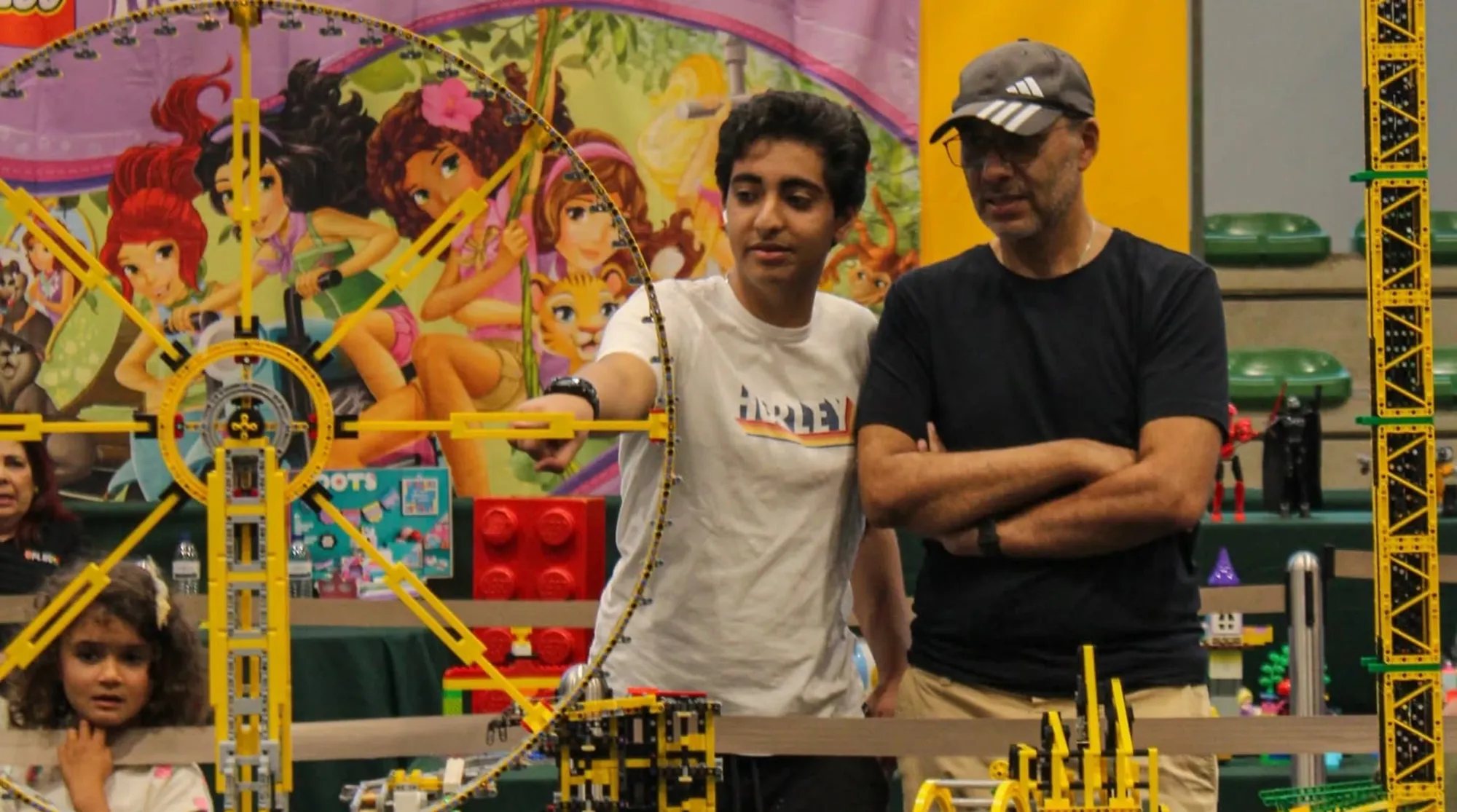 Two visitors admire a yellow LEGO roller coaster structure at BRInCKa 2026 event in S. João da Madeira.