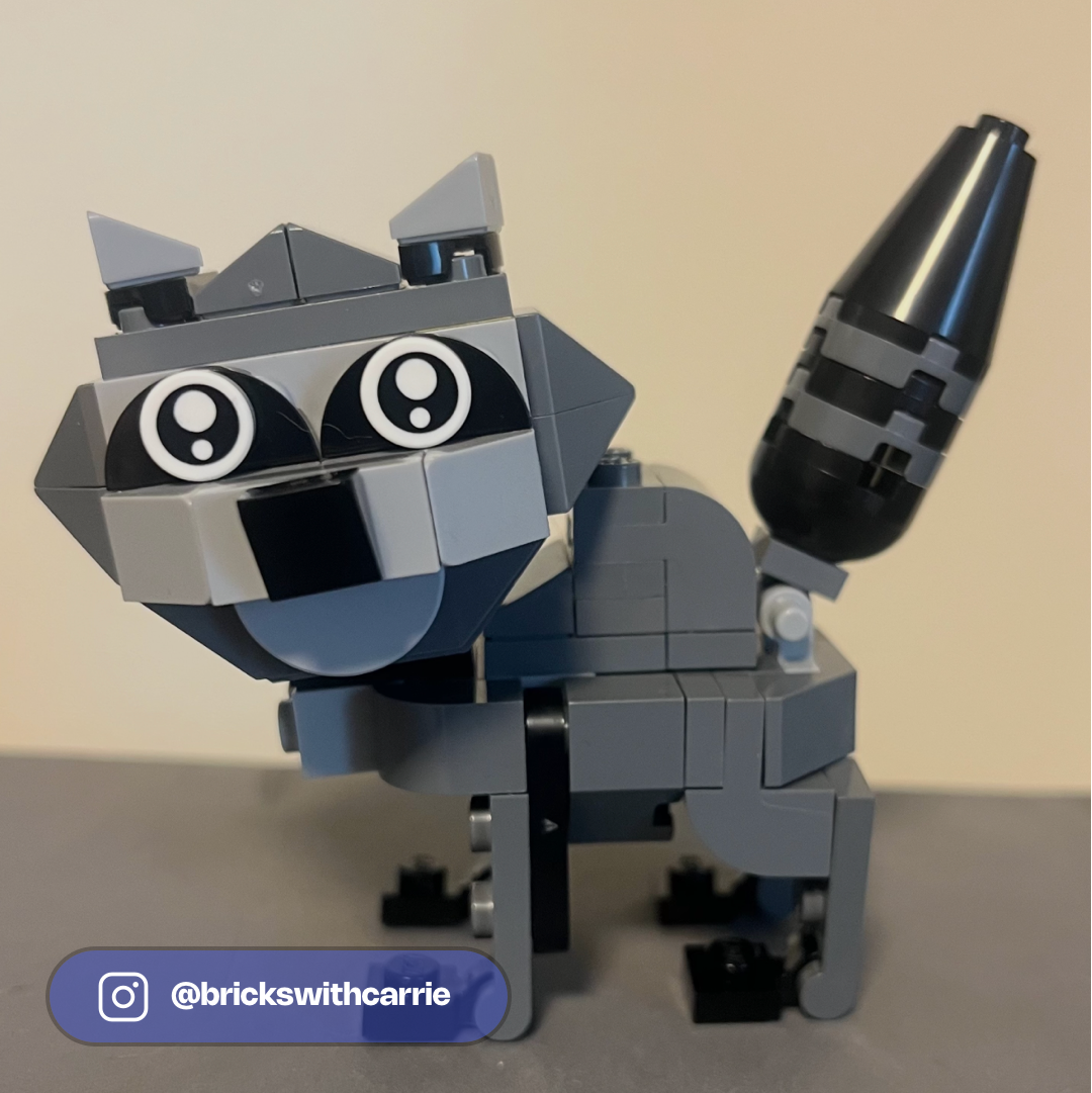 LEGO raccoon MOC with large expressive eyes, gray and black blocks, holding a black blaster weapon.