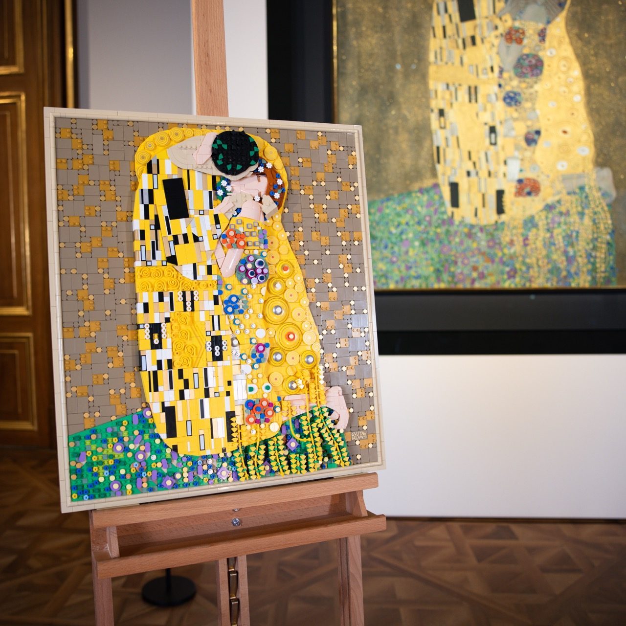 LEGO Art Gustav Klimt's "The Kiss" set displayed on wooden easel in gallery setting.