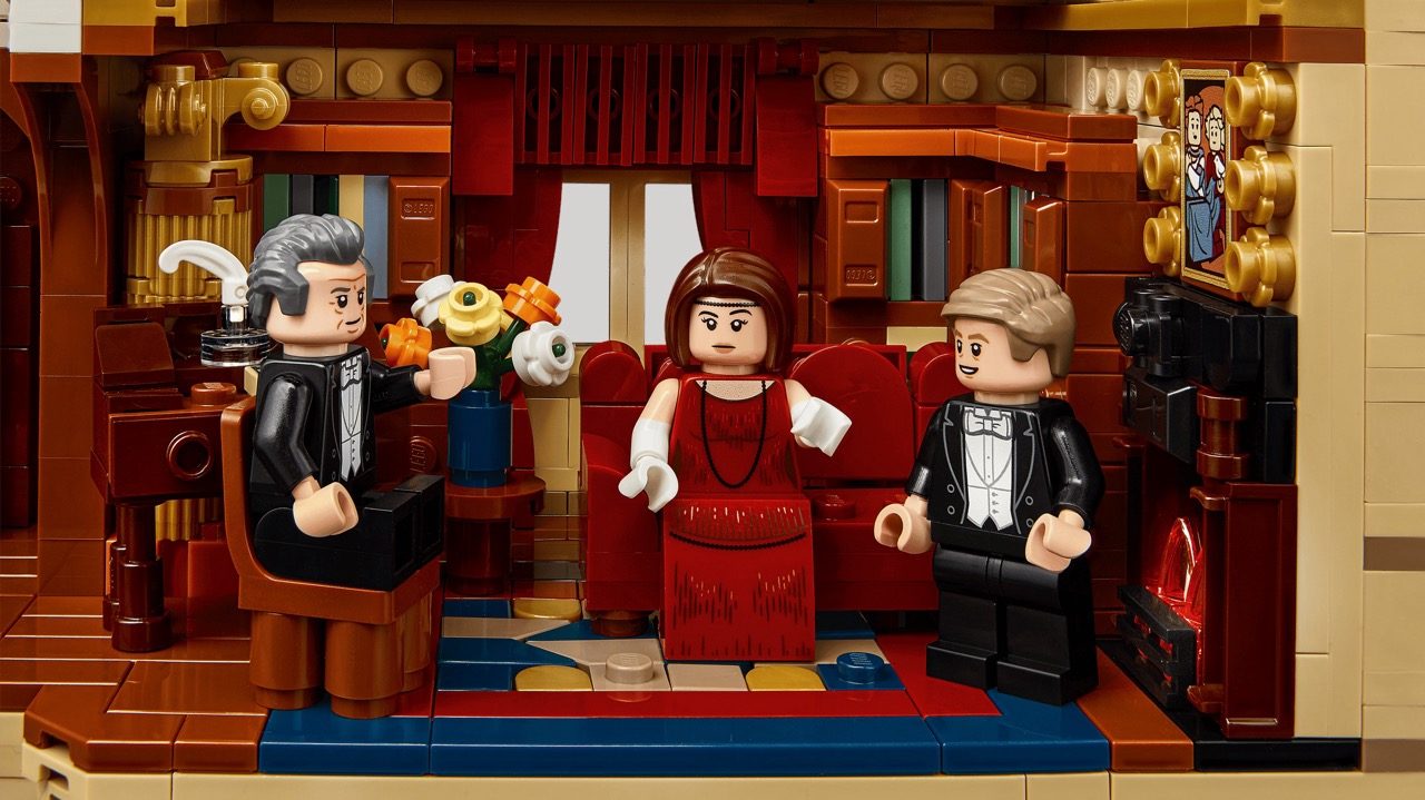 LEGO Downton Abbey set featuring three minifigures in formal attire inside an ornate red and gold interior room.