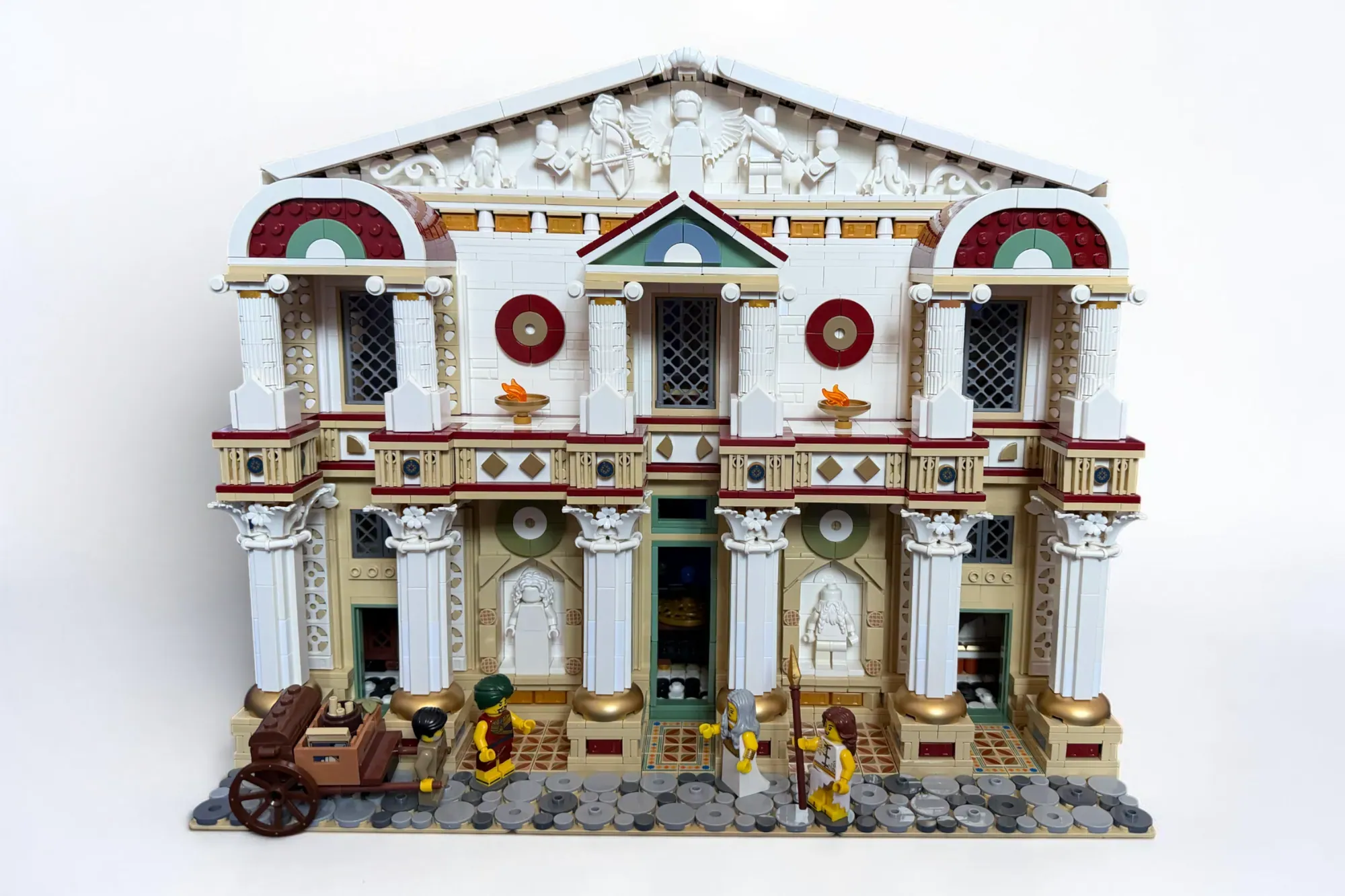Elaborate LEGO classical building with white columns, red and green accents, multiple minifigures, and detailed architectu…