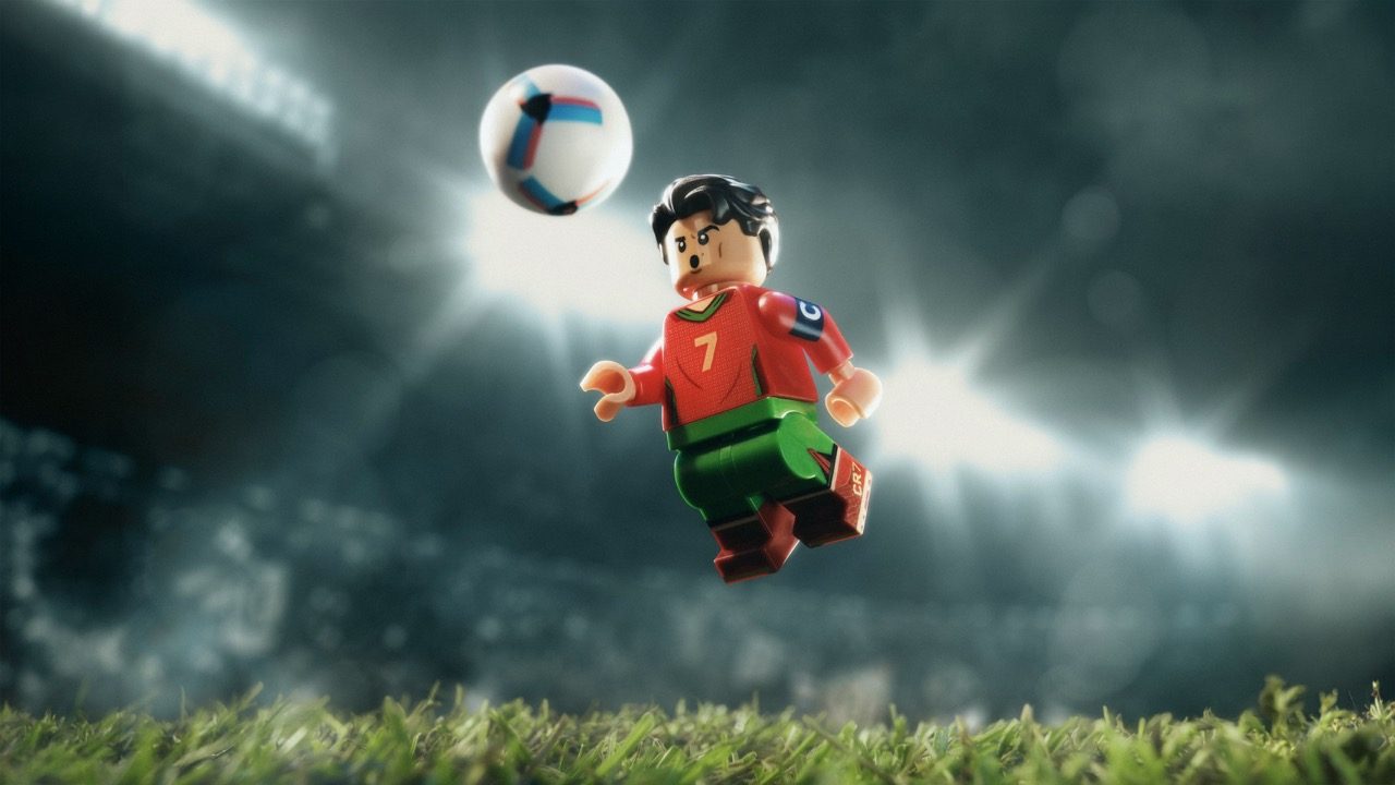 LEGO minifigure soccer player in red jersey jumping to head ball on grass field.