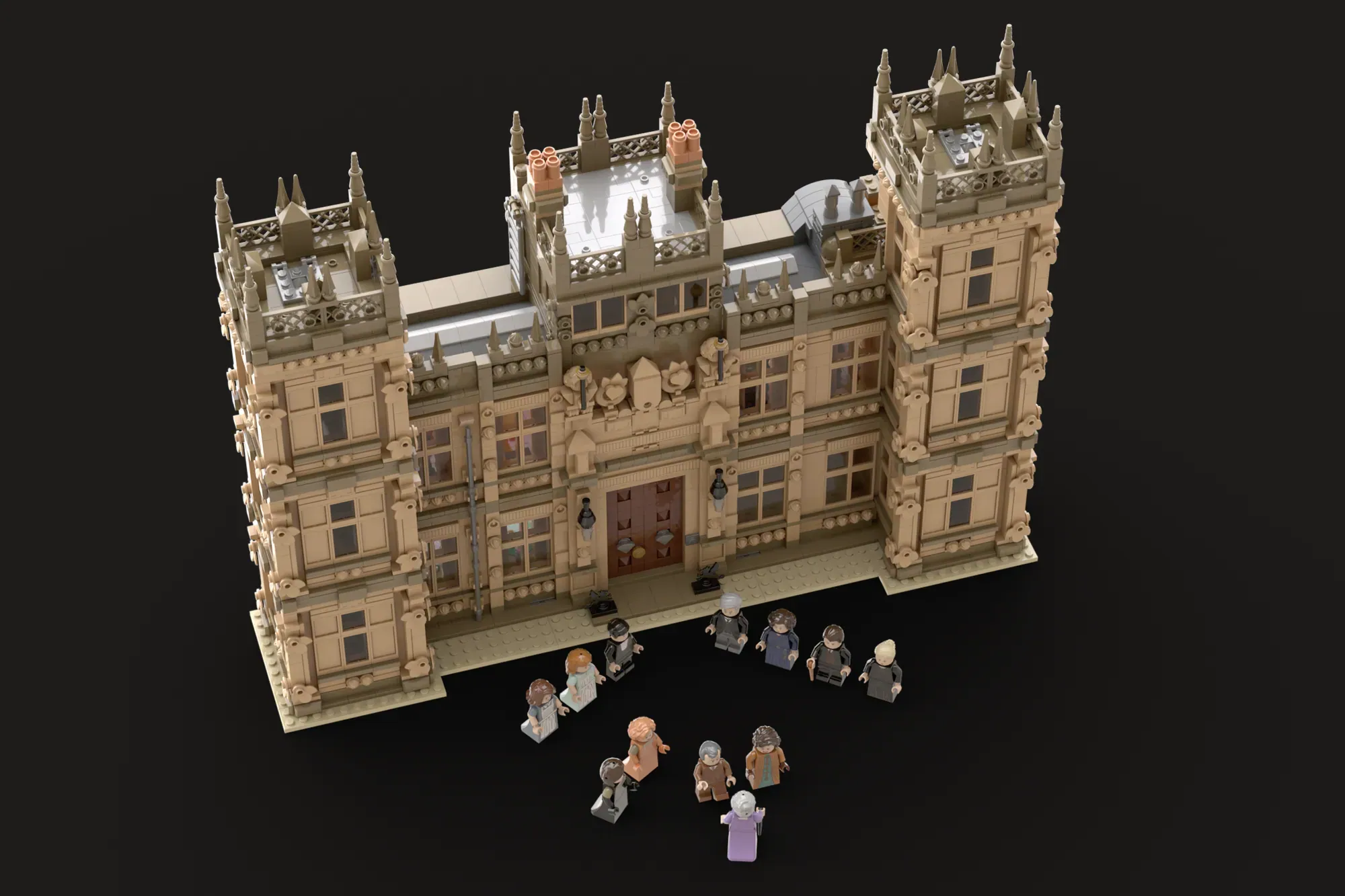 LEGO Downton Abbey castle set with detailed Gothic architecture and minifigures arranged in front.