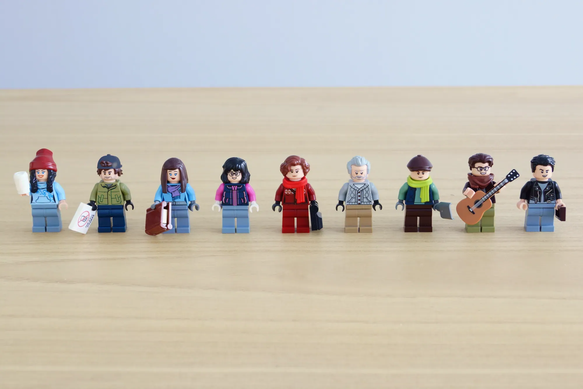 Nine LEGO minifigures representing Gilmore Girls characters lined up on a wooden surface.