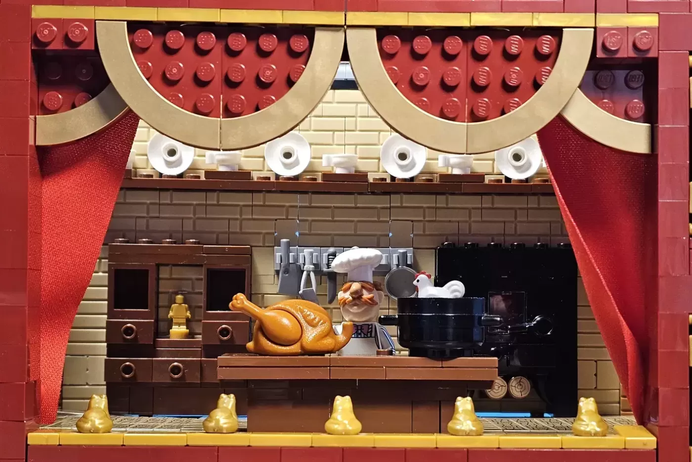 LEGO Muppet Theatre stage set with chef minifigure, roasted turkey, kitchen details, red curtains, and golden decorative e…