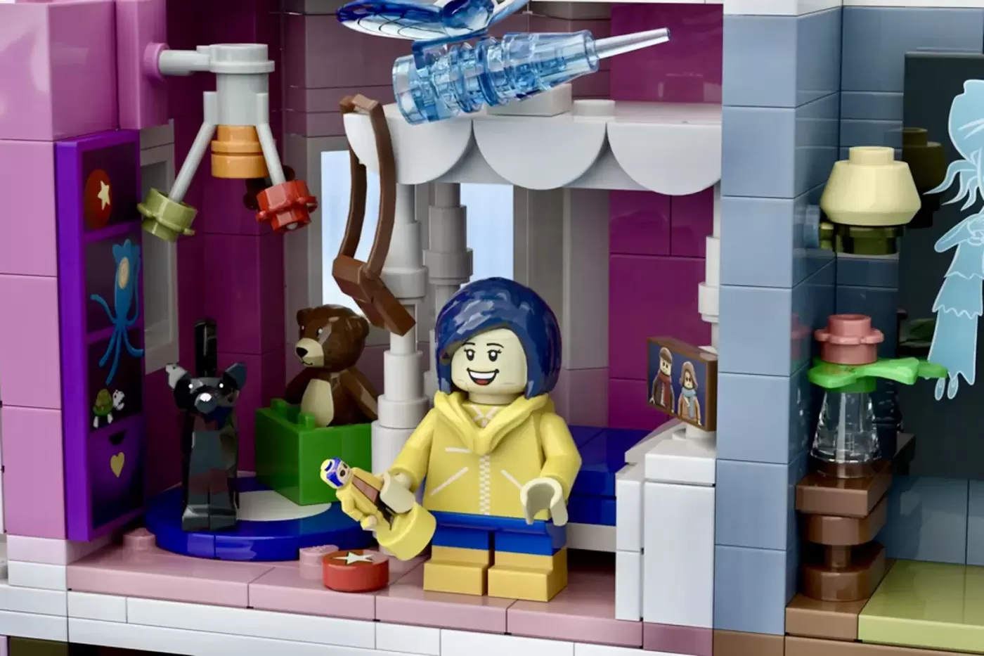 LEGO Coraline minifigure in yellow raincoat in the Pink Palace with bear, cat, and decorative details.
