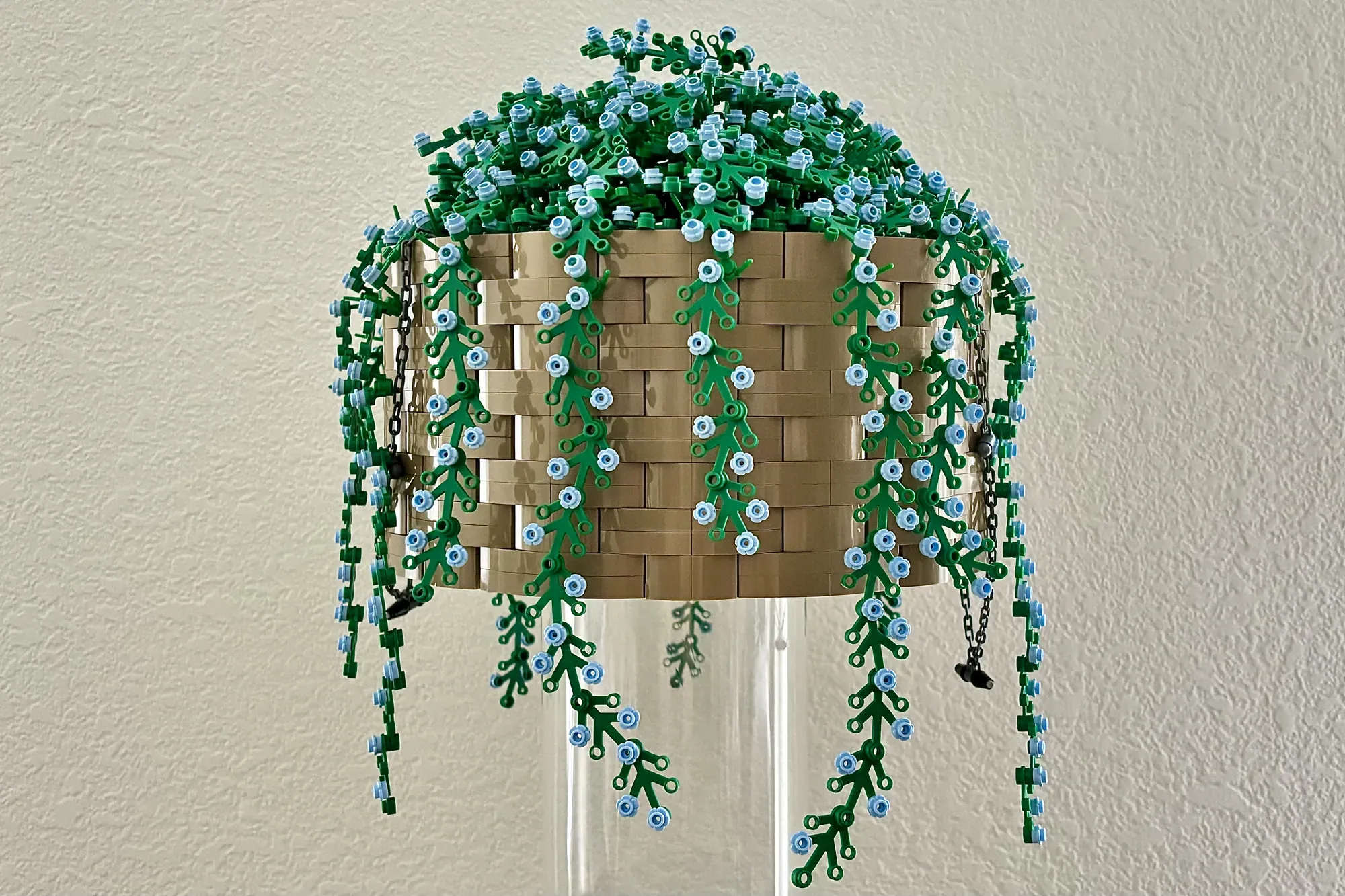 LEGO hanging flower basket with tan woven base, cascading green vines and blue flowers suspended from chains.