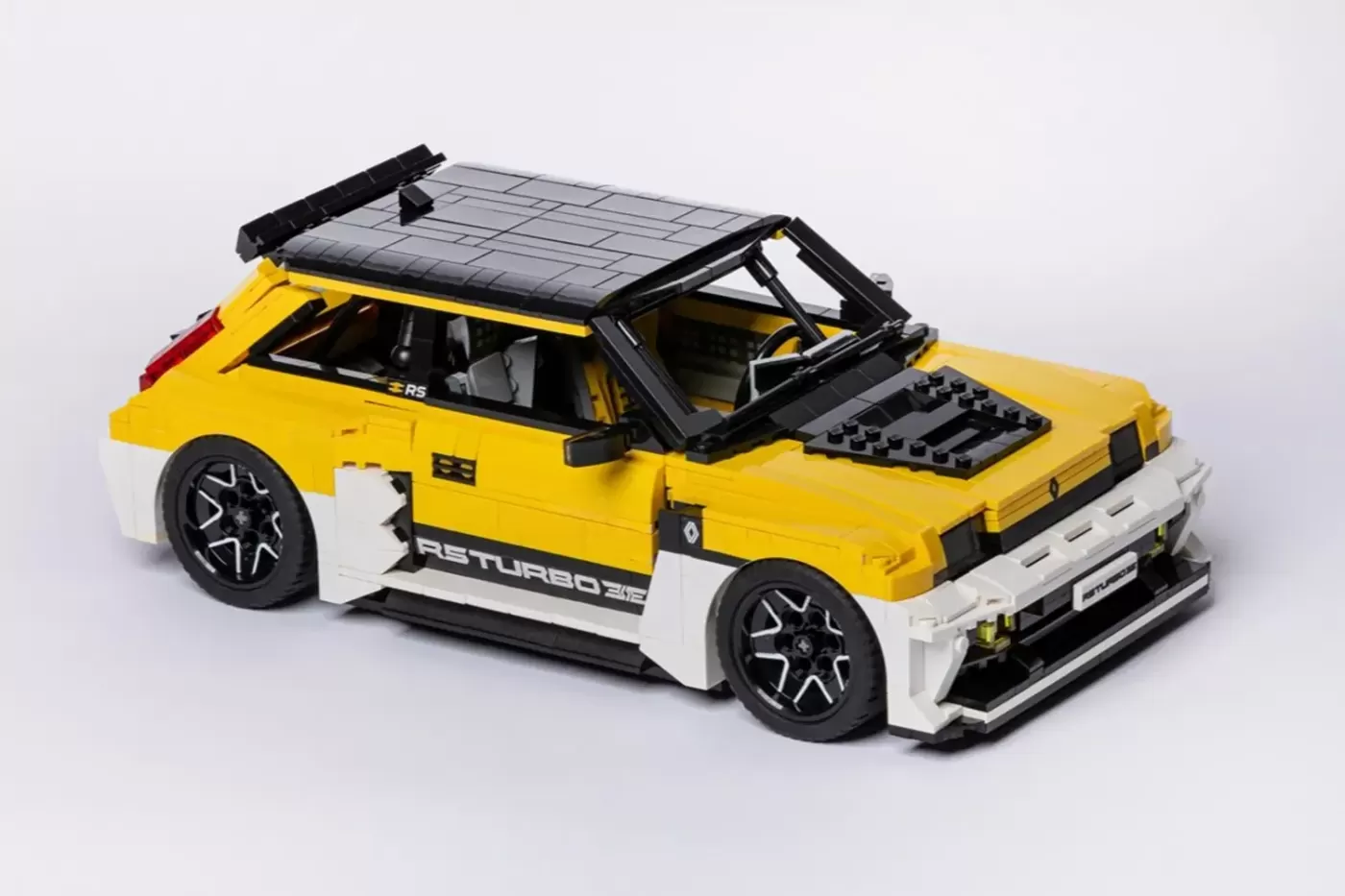 LEGO Renault 5 Turbo 3E model in yellow and white with open door, solar panel roof, and detailed engine hood.