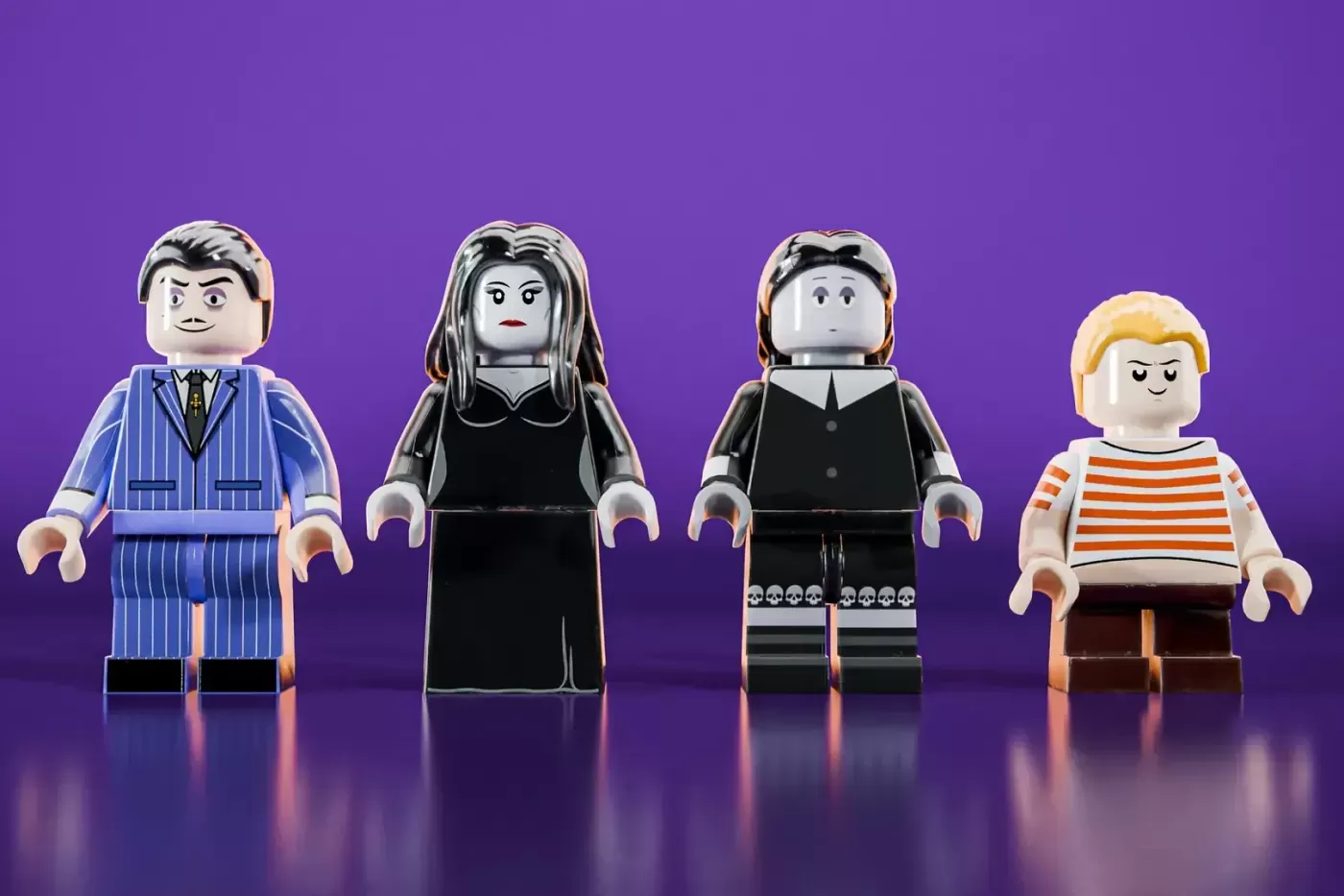 Four LEGO minifigures from The Addams Family against a purple background: Gomez, Morticia, Lurch, and Pugsley.