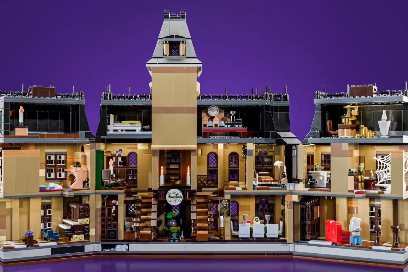 LEGO Addams Family Mansion set displayed in cross-section showing detailed interior rooms across multiple floors with tower.
