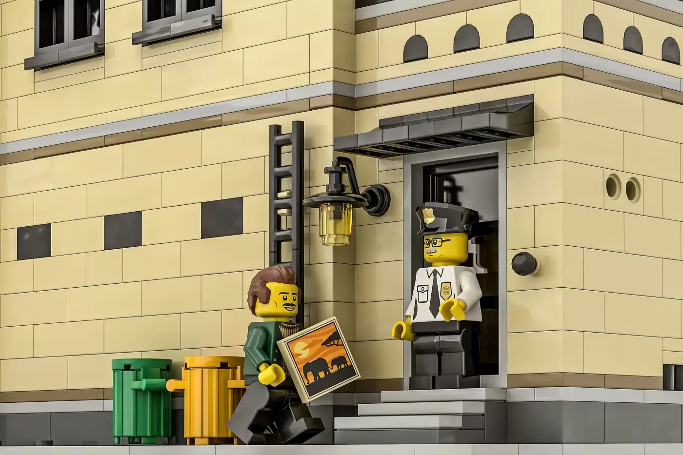 LEGO Clocktower Art Gallery with two minifigures, trash cans, and framed artwork outside cream-colored building entrance.