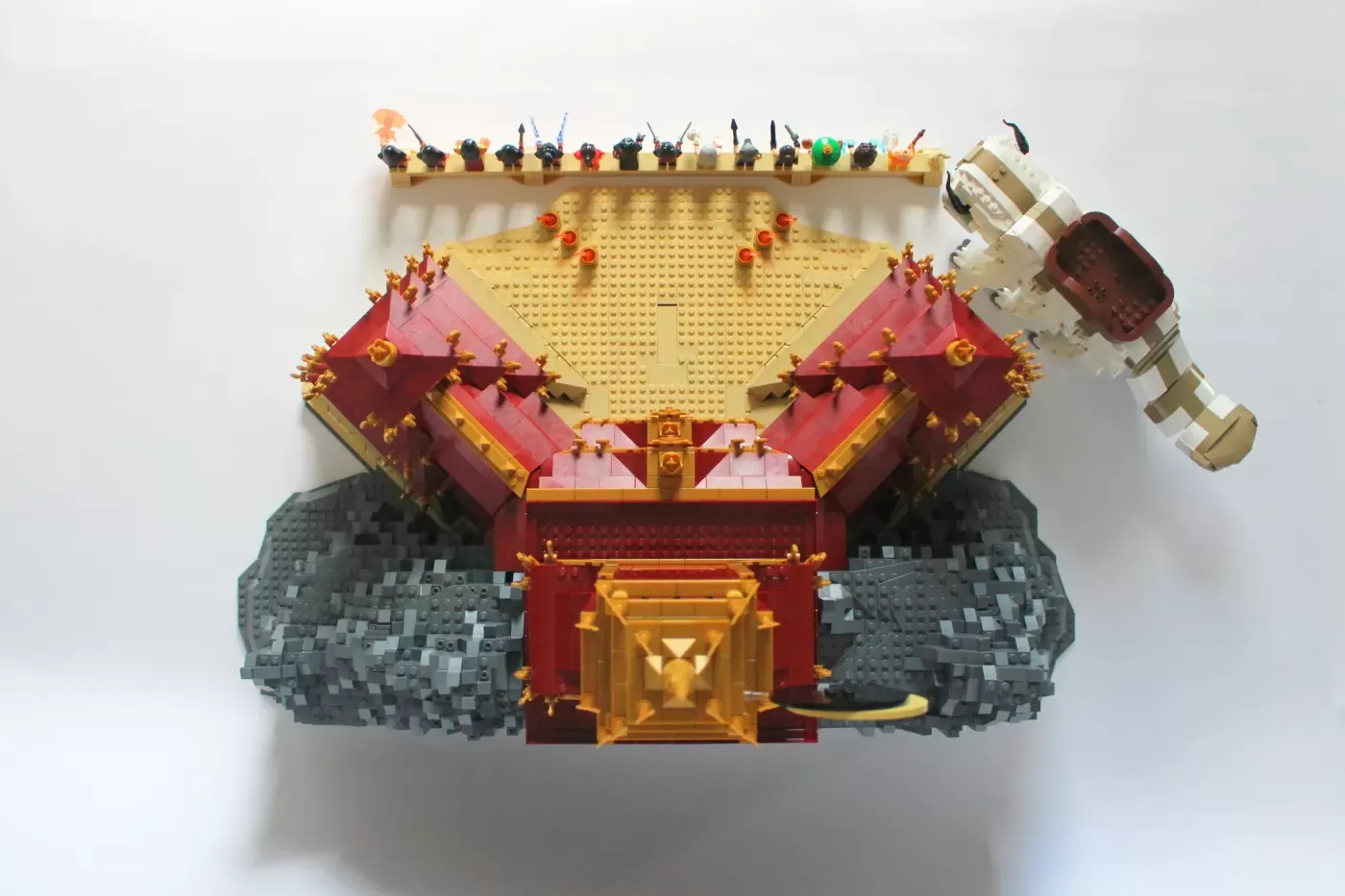 LEGO Fire Nation Palace with red roofs, gold details, gray stone base, minifigures on top tier, and Appa figure on right s…