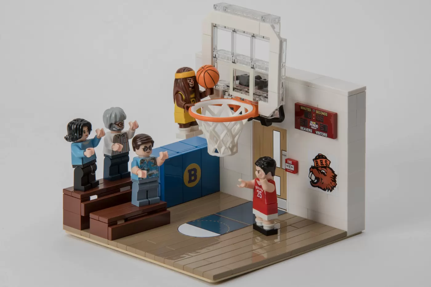 LEGO basketball gym scene with minifigures playing, scoreboard, and hoop with orange rim.