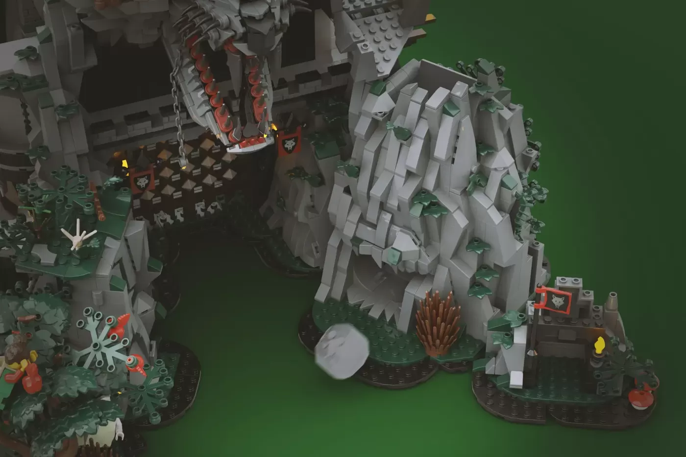Overhead view of elaborate LEGO castle built into giant stone wolf head with green baseplate and detailed landscaping.